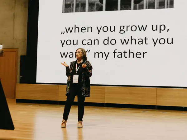 A keynote speaker on stage in front of a slide