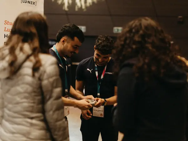 Two exhibitors showing students a small object