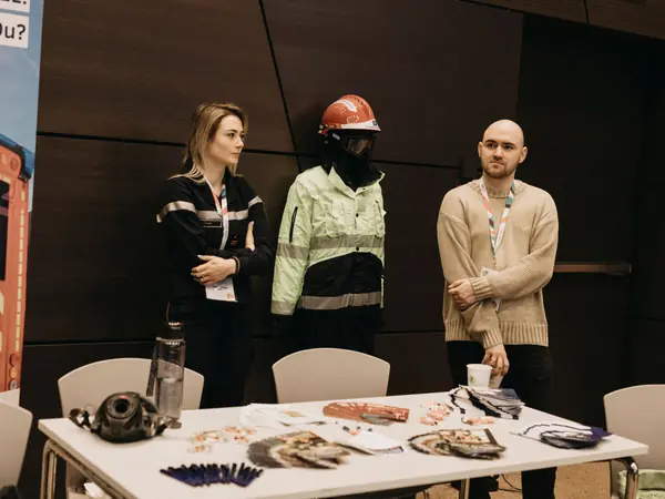 Exhibitors in protective work clothing at their stand