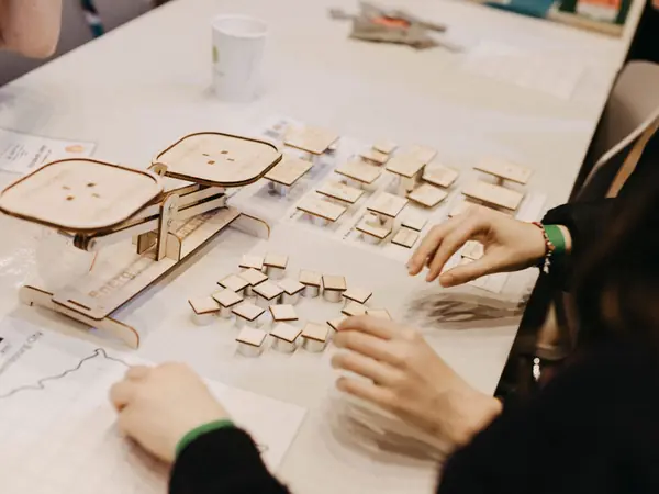Students building with wooden pieces at a workshop table